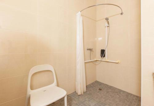 a shower with a white chair in a bathroom at B&B HOTEL Mont-de-Marsan in Saint-Avit