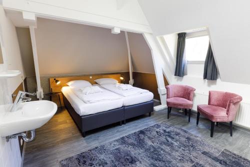 a bedroom with a bed and two chairs and a sink at B&B Landgoed De Grote Beek in Eindhoven