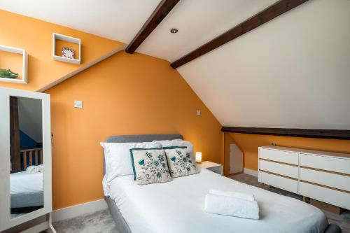 a bedroom with orange walls and a bed in a room at Beautiful 4-Bedroom Cottage Pass the Keys in Rickmansworth