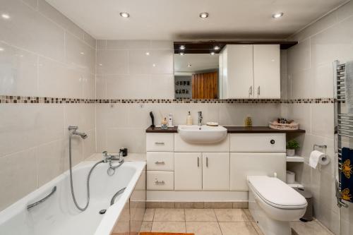 a bathroom with a tub and a sink and a toilet at Beautiful 4-Bedroom Cottage Pass the Keys in Rickmansworth