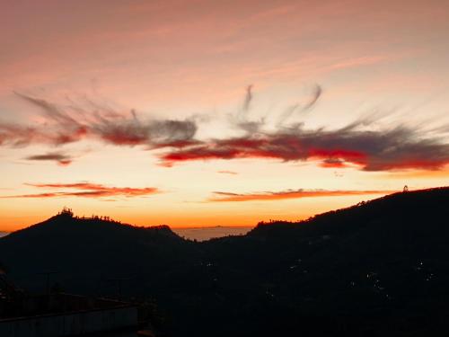 a sunset over a mountain range with a sky at Bruton resorts in Kodaikānāl