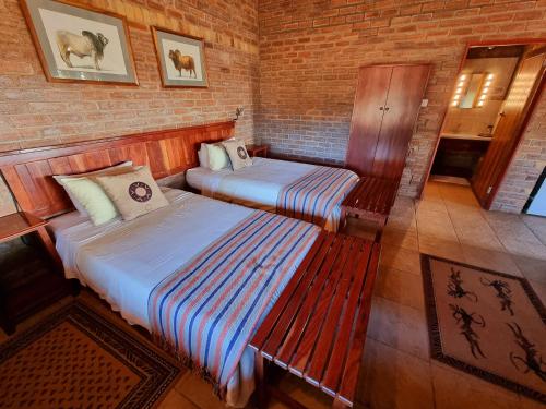 a room with two beds and a bench in it at Wayside Chalets in Tantebane