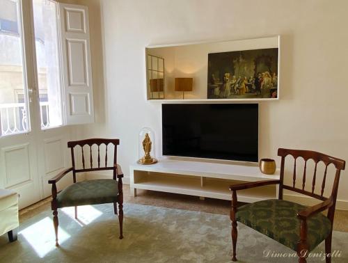 ein Wohnzimmer mit zwei Stühlen und einem Flachbildfernseher in der Unterkunft Dimora Donizetti 5 in Carovigno