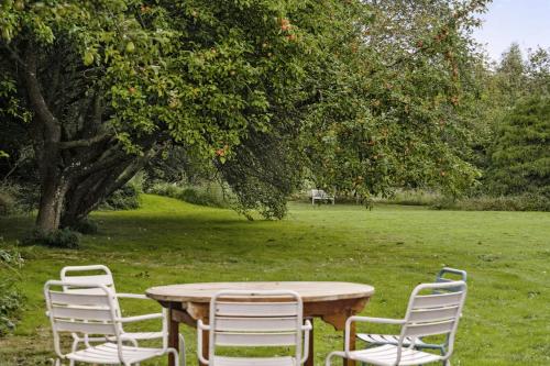 a table with four chairs around it in a field at By The Bay A Thatched House Lies So Beautifully in Føns