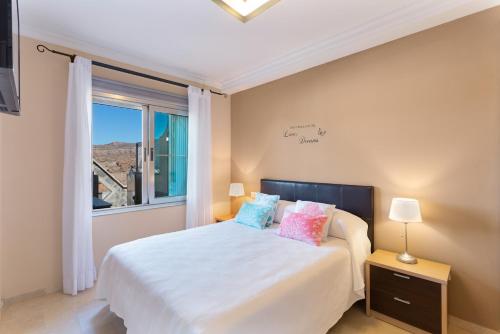a bedroom with a white bed with pillows and a window at Brisas de Puerto Rico in Mogán