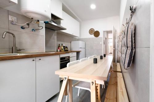 a kitchen with white cabinets and a wooden table at Riverfront Elegance 41BR Spacious Retreat in Lisbon