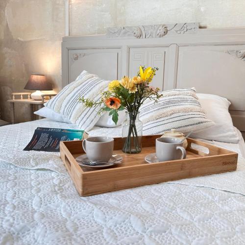 - un plateau avec deux tasses et un vase de fleurs sur le lit dans l'établissement La Maison des Hautures, à Arles