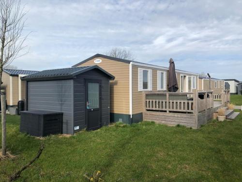 a house with a deck and a black shed at Gemütliches Chalet in Strandnähe in Oostkapelle