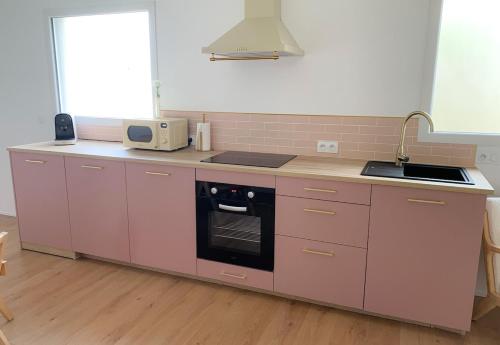 a pink kitchen with a sink and a stove at Le Cocon Rose Jacuzzi privé rêve et Douceur in Belin-Beliet