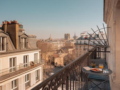 une table avec une assiette de nourriture sur un balcon dans l'établissement Hôtel du Savoir, à Paris