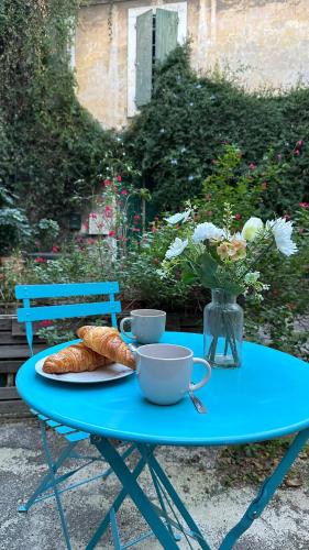 a blue table with a plate of croissants and cups on it at La Maison des Hautures - Ancien Couvent avec Extérieur Proche Arénes- Idéal Familles ou groupe in Arles