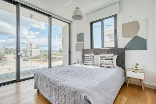 a bedroom with a large bed and large windows at Avenue 101 2 BED in Paphos