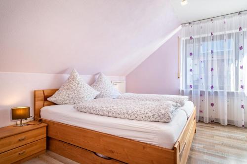 een slaapkamer met een bed met witte lakens en een raam bij Ferienwohnung bei Fredy in Langenargen