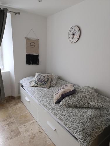 - un lit avec 2 oreillers et une horloge murale dans l'établissement Logement le gabian, à Ampus
