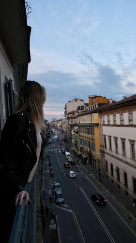 a woman standing on a balcony looking at a city street at DH Rooms Spiga in Milan