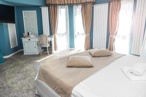 a bedroom with a large bed with blue walls and windows at Villa Boutique Lafayette in Bucharest