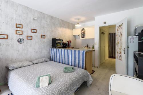 une petite chambre avec un lit et une cuisine dans l'établissement Le Pagnol - Studio proche plage, au Grau-du-Roi
