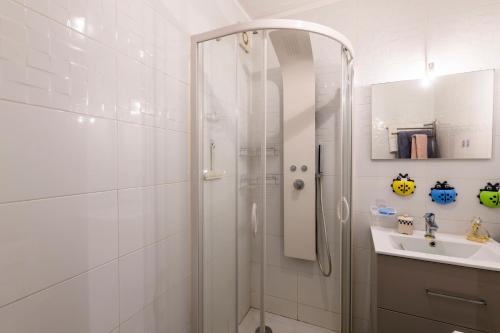une salle de bain blanche avec une douche et un lavabo dans l'établissement Le Pagnol - Studio proche plage, au Grau-du-Roi