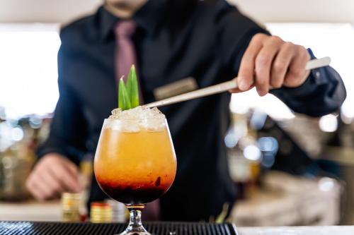 a man is making a drink in a glass at Lindos Village Resort & Spa - Adults Only in Líndos