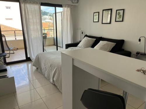 une chambre blanche avec un lit et un balcon dans l'établissement Studio centre Cannes, piscine, climatisation, à Cannes