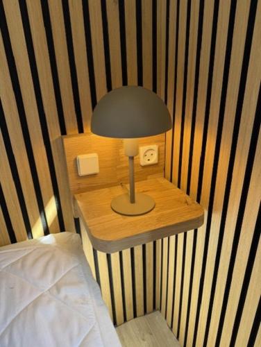 a lamp on a table next to a bed at Folsted - Værelse 100 med eget badeværelse og fri parkering in Bindslev