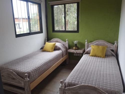two beds in a room with green walls and windows at Arawi Cabaña in Merlo