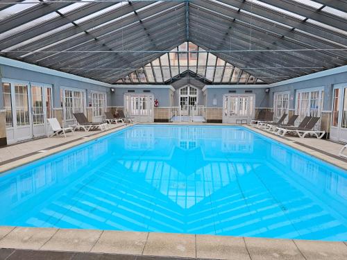 une grande piscine avec des chaises et un plafond dans l'établissement Appartement en résidence avec piscine, à Le Touquet-Paris-Plage