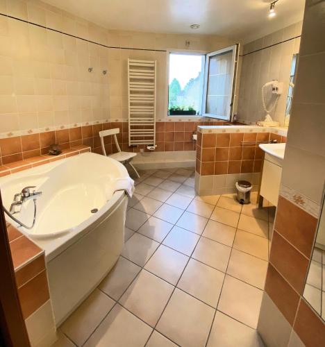 une grande salle de bain avec une baignoire et un lavabo dans l'établissement Le Clos de la Barre- Chambres d'hôtes de charme en Normandie-BASLY-Proche plage débarquement, à Basly