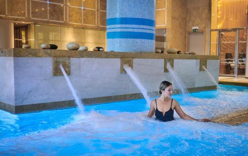 a woman is sitting in a swimming pool at Divani Apollon Palace & Thalasso in Athens