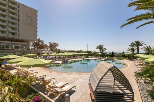 a swimming pool with lounge chairs and umbrellas at a resort at Divani Apollon Palace & Thalasso in Athens