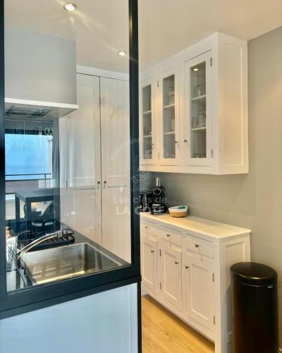 une cuisine blanche avec des armoires blanches et un évier dans l'établissement Bel Horizon - Vue mer et dunes, à Le Touquet-Paris-Plage