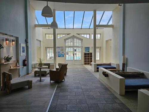 une grande chambre avec des chaises et des tables dans un bâtiment dans l'établissement Appartement en résidence avec piscine, à Le Touquet-Paris-Plage