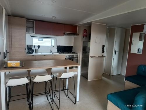 une cuisine avec une table et des tabourets dans une pièce dans l'établissement Camping la yole, à Vendres