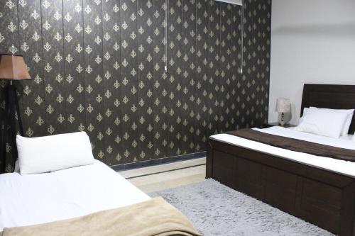 a bedroom with two beds and a wall covered in wallpaper at Vision 2 Islamabad in Islamabad