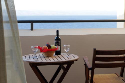 a table with a bottle of wine and a basket of fruit at Sunrise Resort Hotel in Mithymna