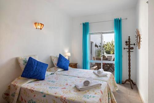 a bedroom with two beds with blue pillows and a window at Maison de vacances Casa Rocha in Armação de Pêra
