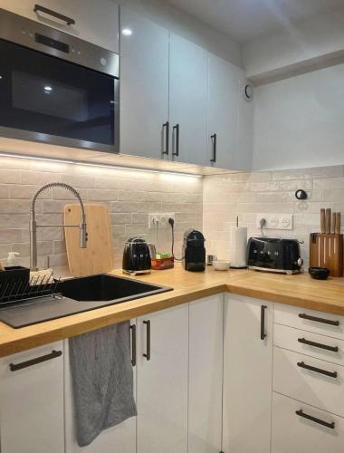 une cuisine avec des armoires blanches et un évier dans l'établissement Parisian Chic Near Opera Louvre, à Paris