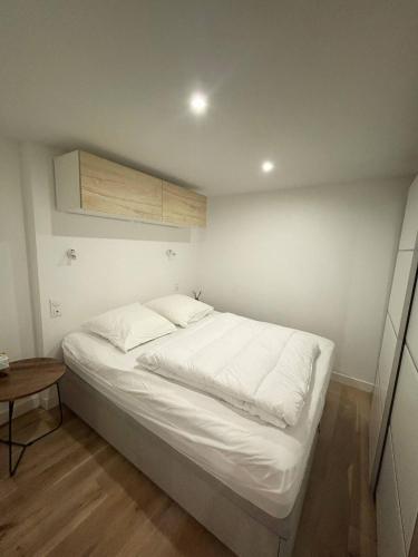 - un lit blanc dans une chambre avec une table en bois dans l'établissement Parisian Chic Near Opera Louvre, à Paris