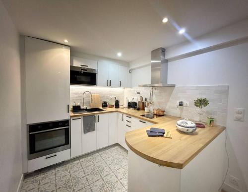 une cuisine avec des armoires blanches et un comptoir en bois dans l'établissement Parisian Chic Near Opera Louvre, à Paris