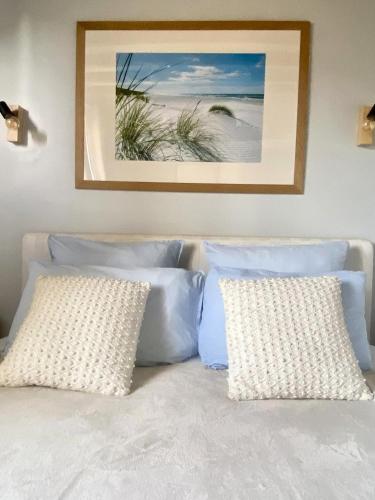 - un lit avec deux oreillers et une photo de plage dans l'établissement Le Clos de la Barre- Chambres d'hôtes de charme en Normandie-BASLY-Proche plage débarquement, à Basly