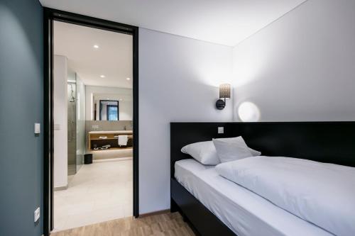 a bedroom with a black and white bed and a mirror at Montfort - das Hotel in Feldkirch
