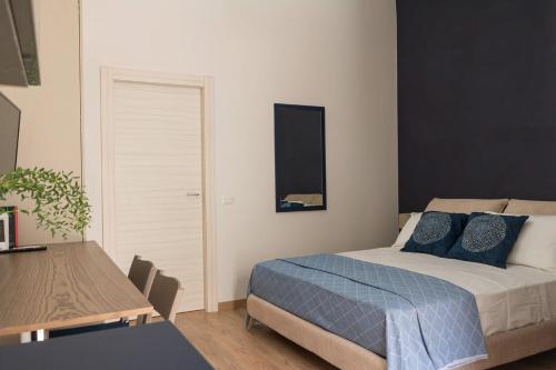 Un dormitorio con una cama con almohadas azules y una mesa. en Monolocale Real Valle Blue, en Scafati