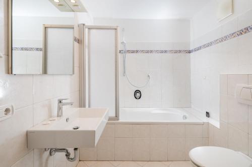 a white bathroom with a sink and a bath tub at Appartements Greif in Malles Venosta