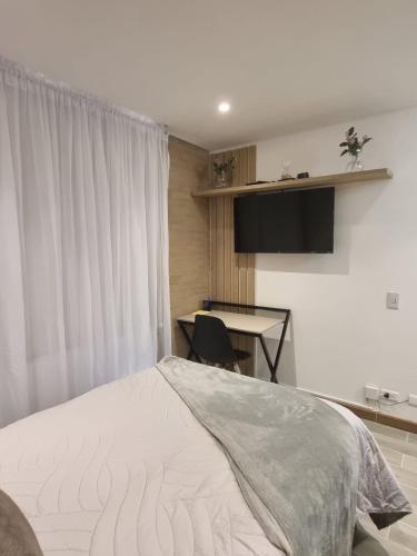 a bedroom with a bed and a desk and a window at Loft con Estilo y Comodidad in Bogotá