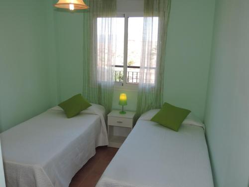 two beds in a small room with a window at Apartamento con Piscina in Tarifa
