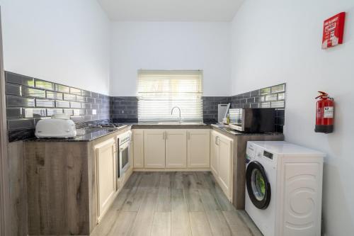 a kitchen with a sink and a washing machine at La Casa Sorento in Victoria