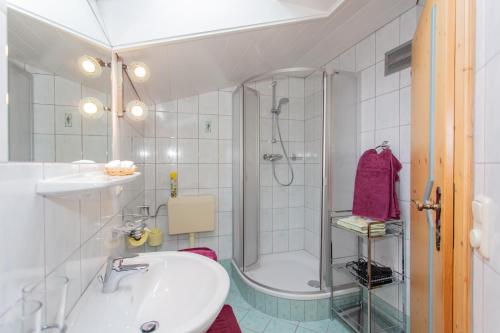 a white bathroom with a shower and a sink at Haus Traudi in Rauris