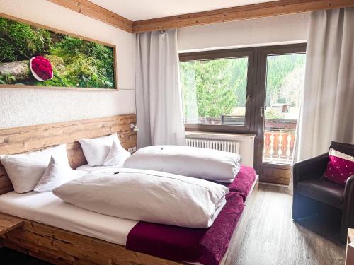 a bedroom with two beds and a chair and a window at Landgasthof Jostalstüble in Titisee-Neustadt