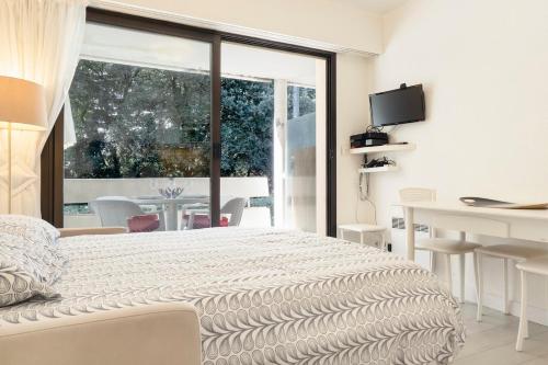 une chambre blanche avec un lit, un bureau et une fenêtre dans l'établissement Studio tout à pied La Baule Les Pins 150m plage, à La Baule