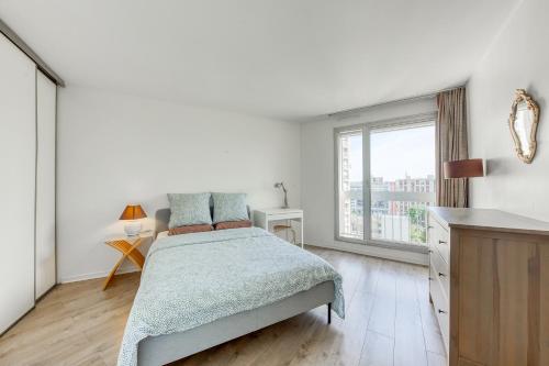 une chambre blanche avec un lit et une grande fenêtre dans l'établissement 4 min walk to Metro, 60m², renovated, La Défense, à Puteaux